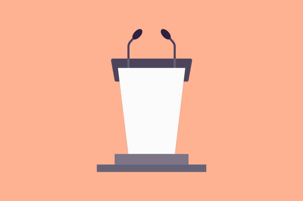 A peach-colored podium with a microphone in front of a stage