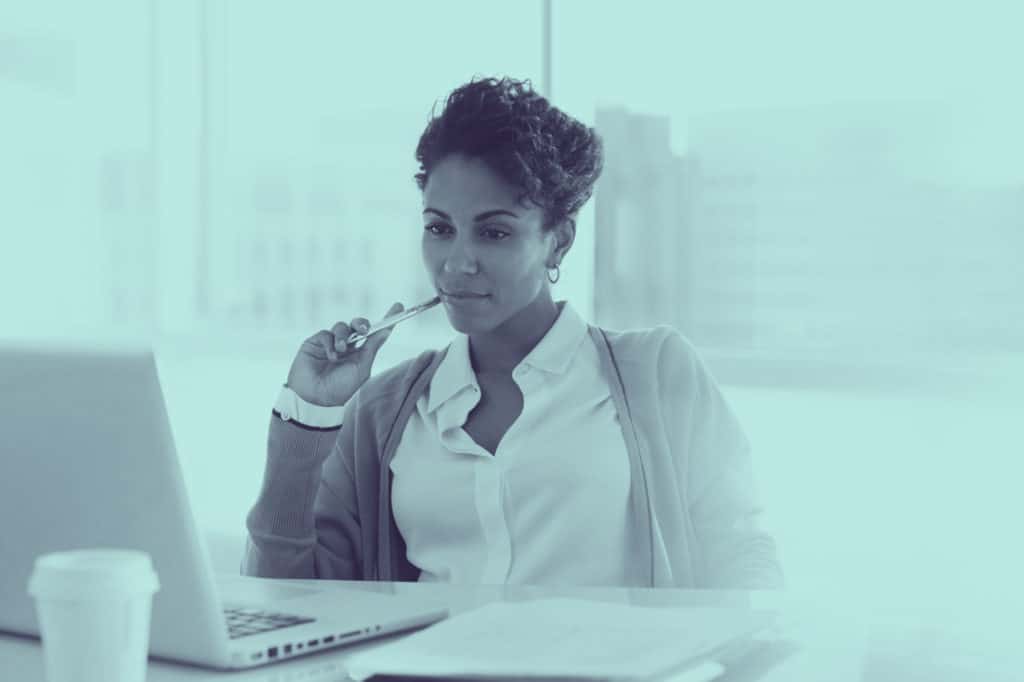 A woman thinking while looking at her laptop