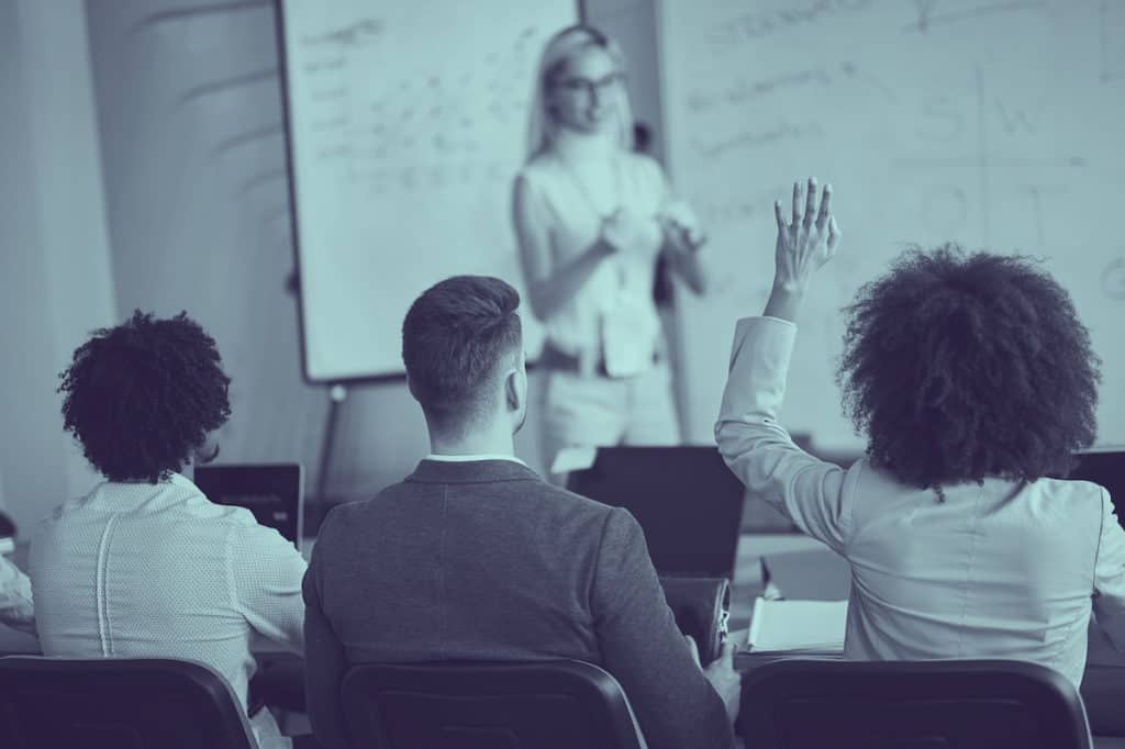 person raising hand in classroom asking why continuous climate education is important for businesses