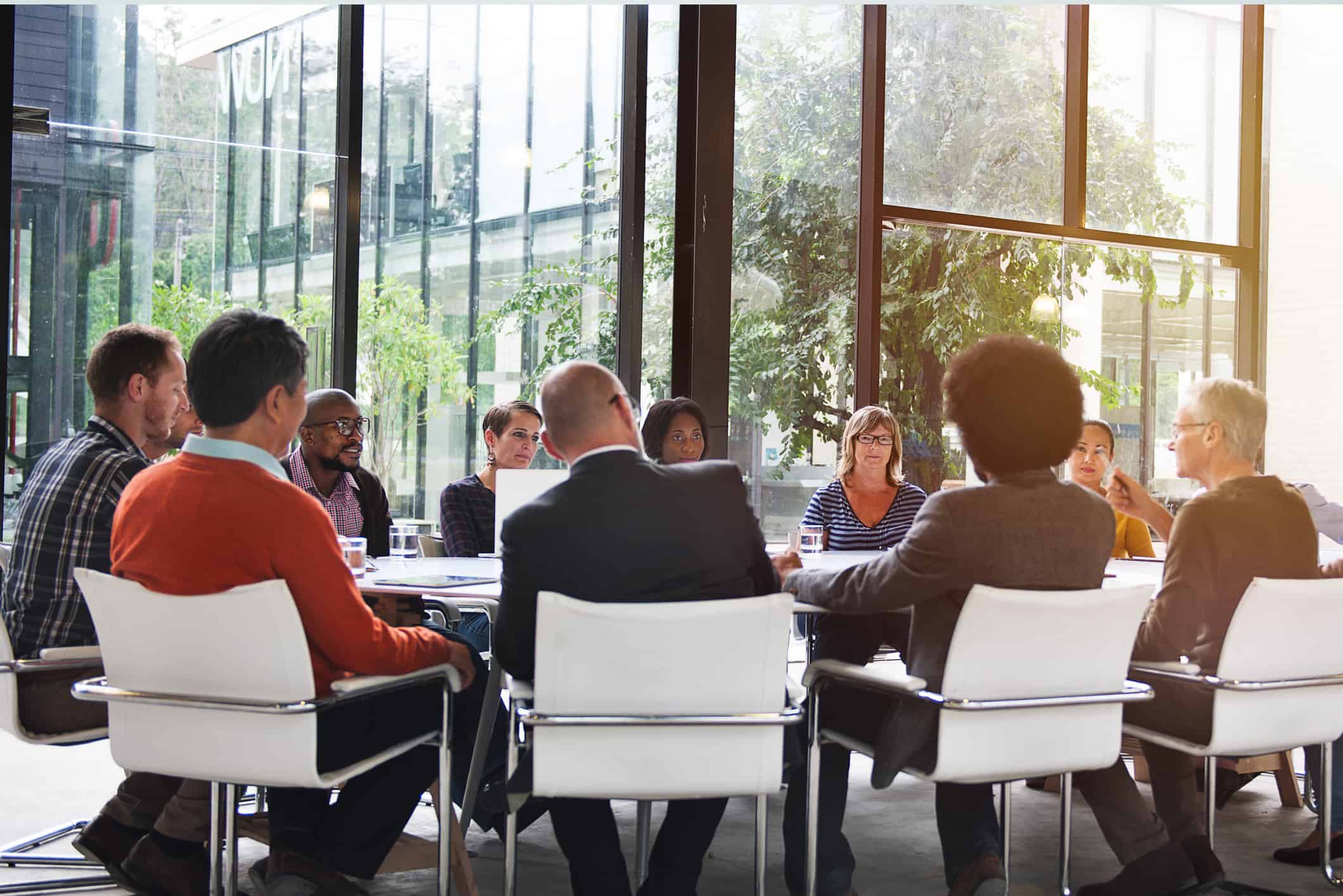 A group of people having a meeting inside a glass-walled conference room