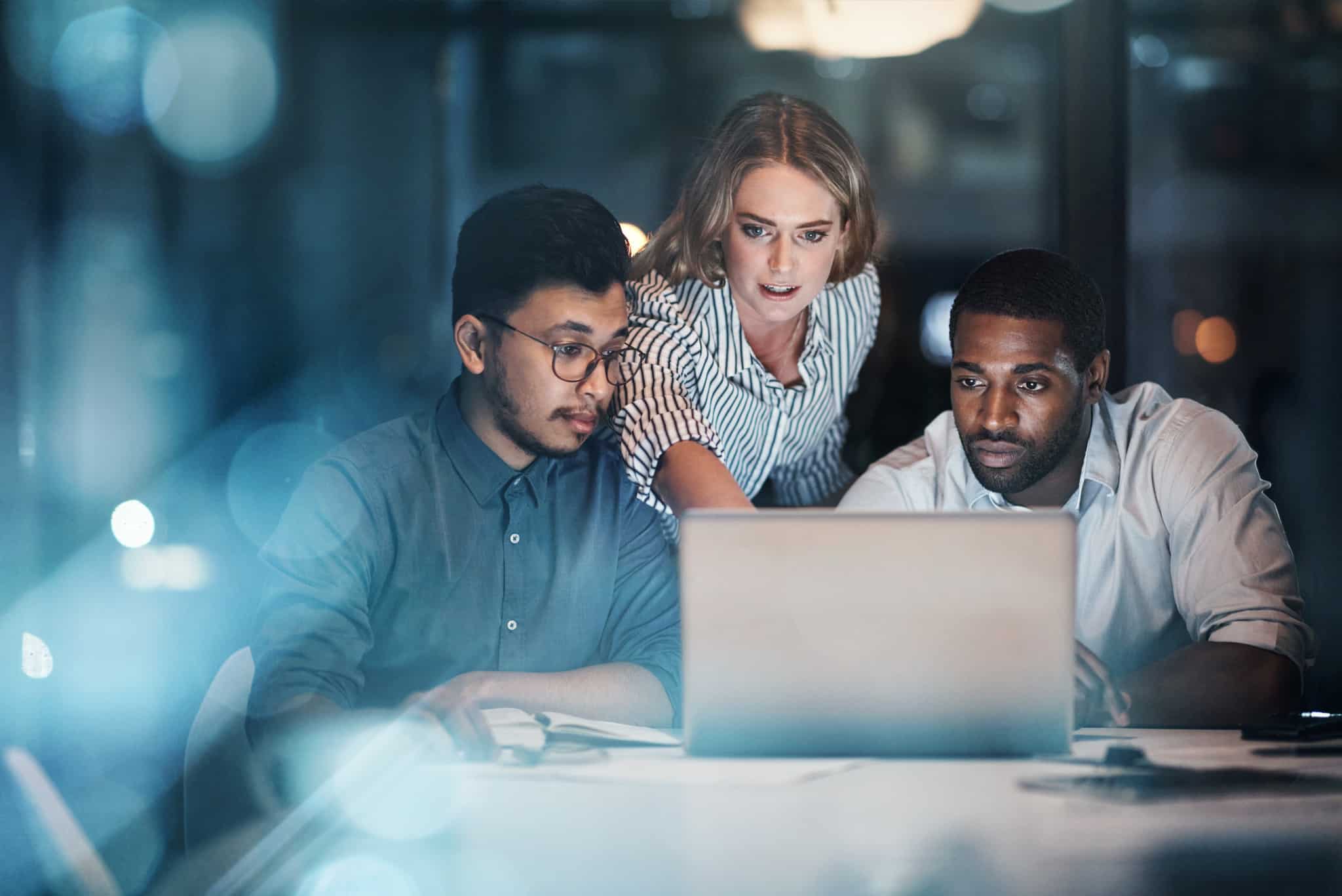 A woman points something on the computer to her colleagues.