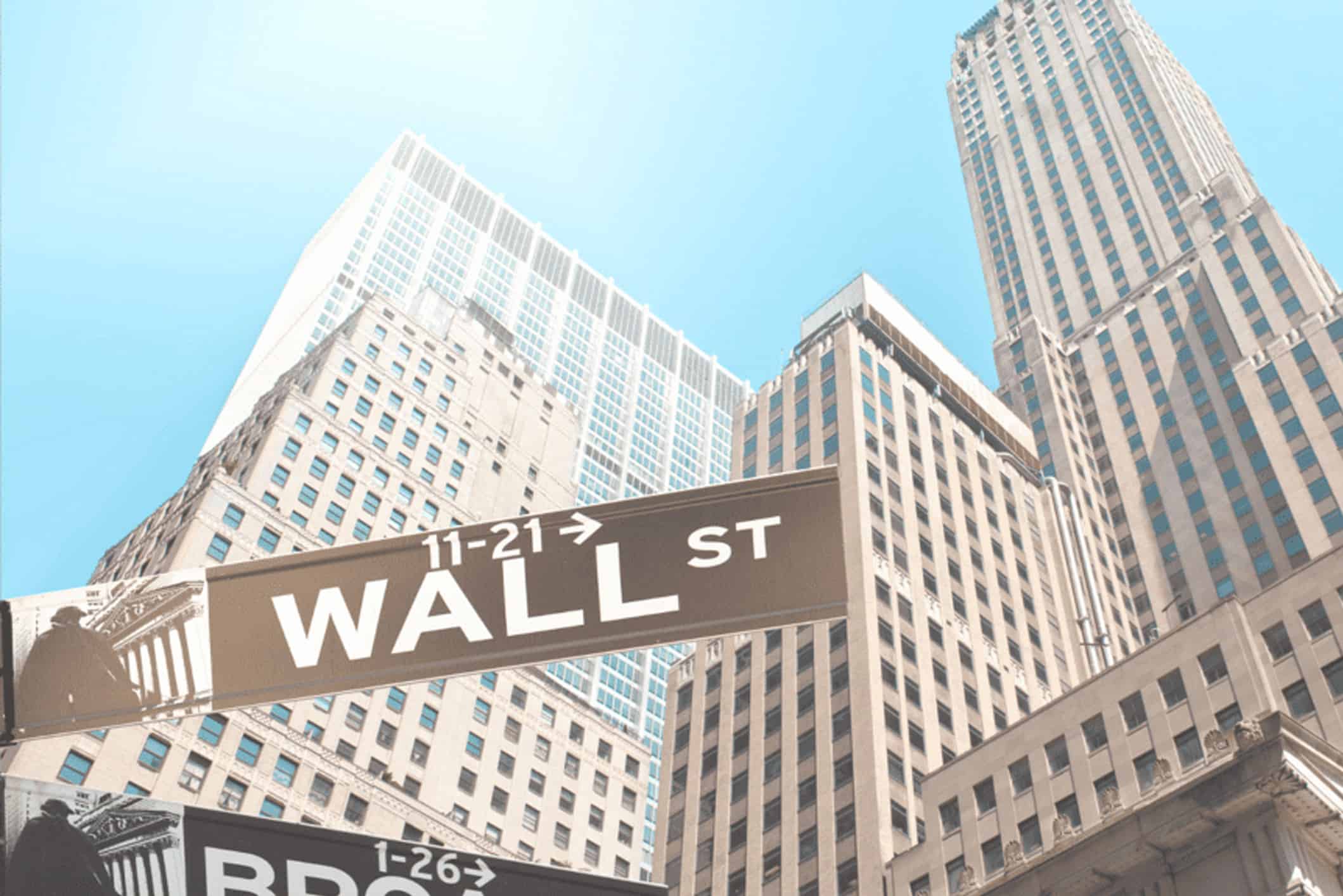 A Wall St. sign with skyscrapers in the background