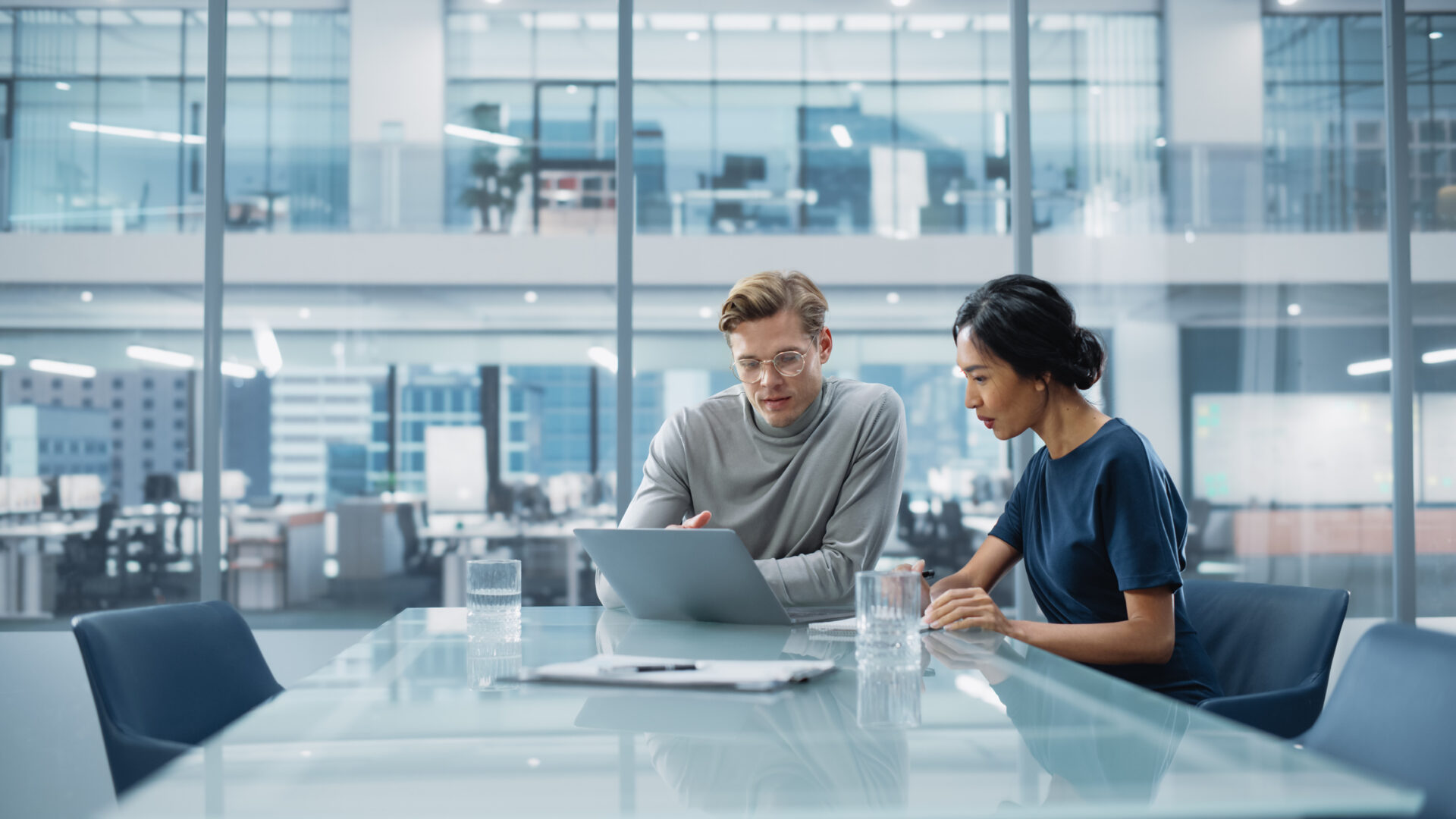 Man and woman looking at laptop in corporate office