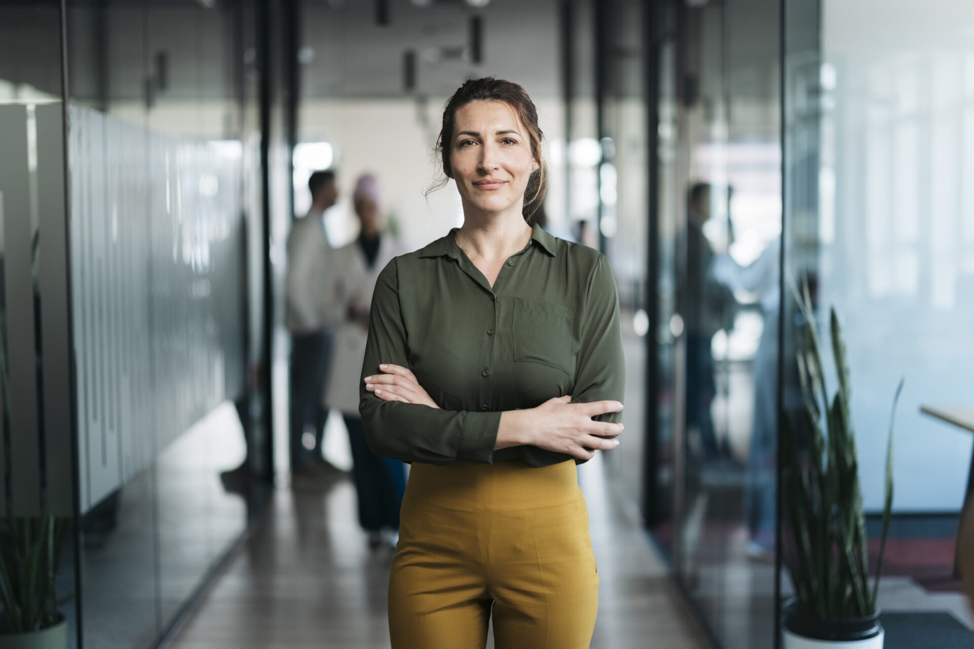 Portrait of a successful businesswoman standing in a modern office hallway, exuding confidence and professionalism